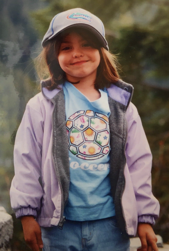 Lia with a purple jacket, soccer t-shirt and UF hat in Washington